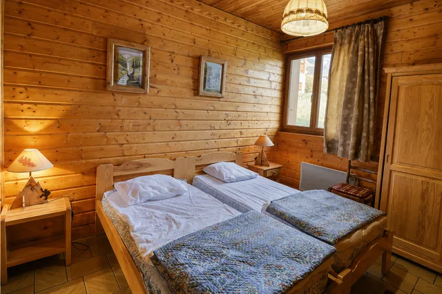 Chambre avec deux lits simples et murs en bois